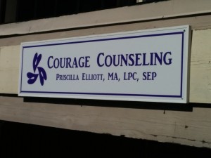 Sign for Courage Counseling hanging from the balcony of Suite 303.